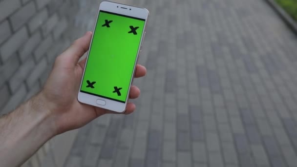 POV, mano masculina sosteniendo la pantalla verde del teléfono inteligente caminando en la ciudad — Vídeo de stock