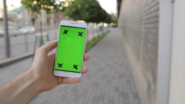 Personne tenant smartphone écran vert marche en ville 