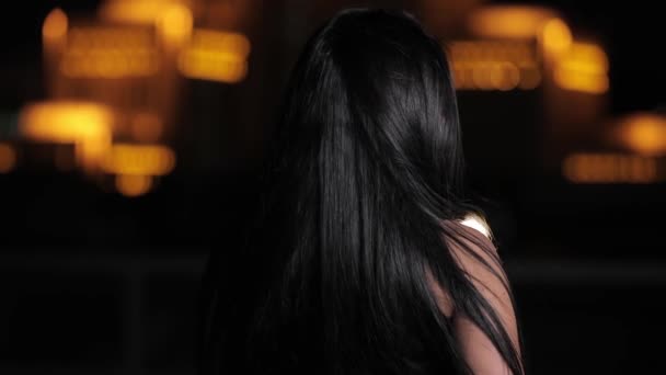 Hezká brunetka vlasy žena obrací tvář a při pohledu na fotoaparát v noční město — Stock video
