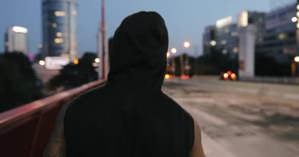 Hombre caminando y pensando en un puente en la noche, vista trasera — Vídeo de stock