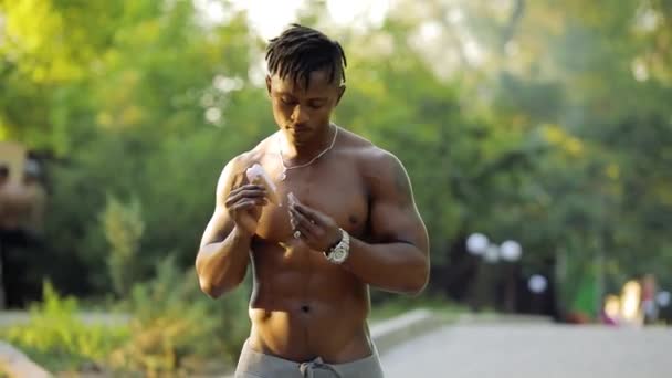African macho man topless eating ice cream walking in park — Stock Video