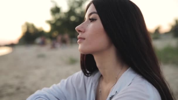 Roztomilá mladá žena portrét sedět u řeky beach — Stock video