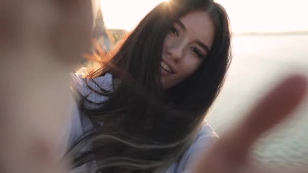 Молодая улыбающаяся женщина держит камеру показывая язык в солнечных лучах, замедленная съемка — стоковое видео