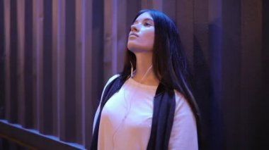 Müzik ve gece şehirde duvara yaslanmış rahatlatıcı kadın