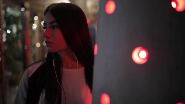 Mujer escuchando música en las lámparas de luz roja de la ciudad nocturna — Vídeos de Stock