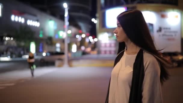 Одинокая женщина, гуляющая ночью по центру города, слушающая музыку и расслабляющая — стоковое видео