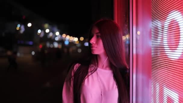 Mujer escuchando música en las lámparas de luz roja de la ciudad nocturna — Vídeos de Stock