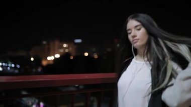 Genç kadın bir köprüde gece yürüyüş müzik dinlemek