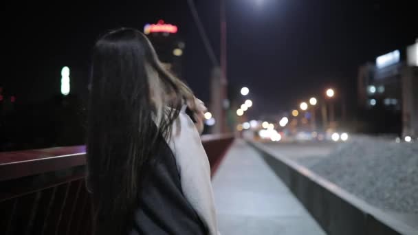 Mulher ouvindo música andando em uma ponte à meia-noite, vista traseira — Vídeo de Stock