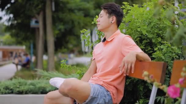 Asian man sitting on city bench and relaxing — Stock Video