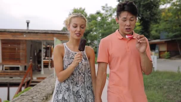 Pareja joven caminando y comiendo helado juntos — Vídeos de Stock