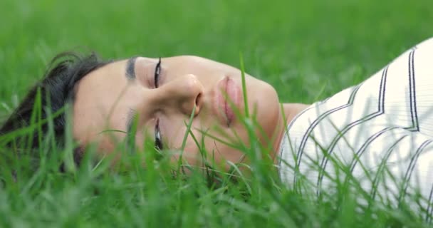 Vrouw liggend in een gras gazon ontspannen, sluit haar ogen en slaap — Stockvideo