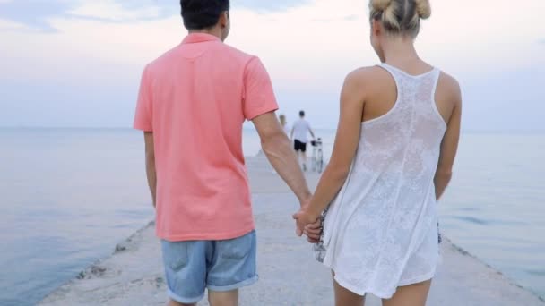 Young couple walking at sea pier holding hands — Stock Video