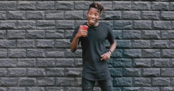 African american man dancing against brick wall listening to music — Stock Video