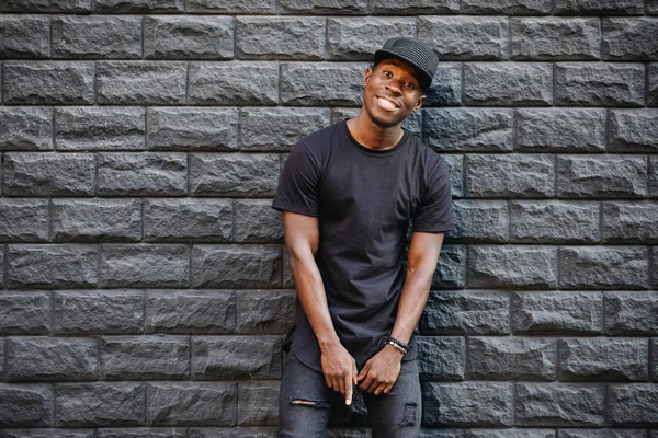 African american fashion male model in blank black t-shirt standing against brick wall