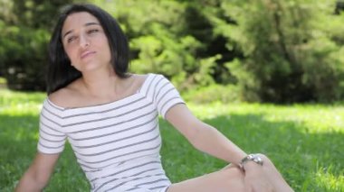 Çim çimenlerin üzerine oturmuş rahatlatıcı kadın