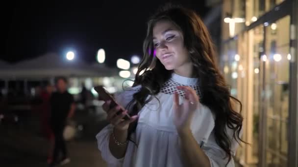 Mulher que navega smartphone usando aplicativo na cidade noturna — Vídeo de Stock