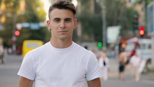 Close-up retrato de jovem bonito homem olhando sorrindo para a câmera, fundo urbano — Vídeo de Stock