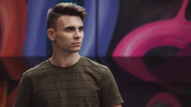 Sokak sanatı duvara poz haki renk polo modelinde yakışıklı adam