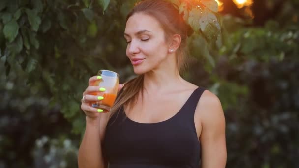 Mujer adulta bebiendo jugo de naranja en un jardín, concepto de estilo de vida saludable — Vídeo de stock