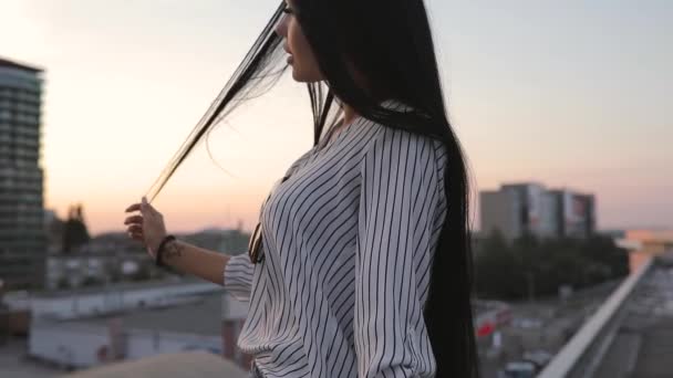 Mujer bien arreglada tocando su hermoso cabello en la azotea al atardecer — Vídeos de Stock