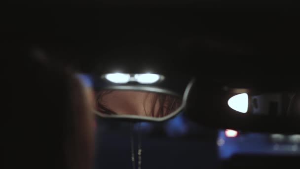 Sexy woman sitting in car salon corrects angle of rearview mirror position — Stock Video