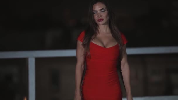 Женщина в сексуальном красном платье гуляет по ночному городу — стоковое видео