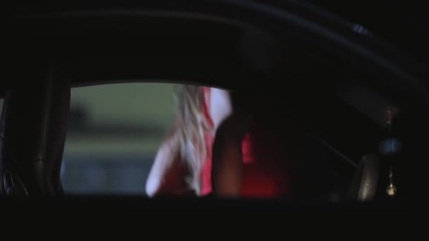 Vrouw in sexy rode jurk zitten in haar auto 's nachts — Stockvideo