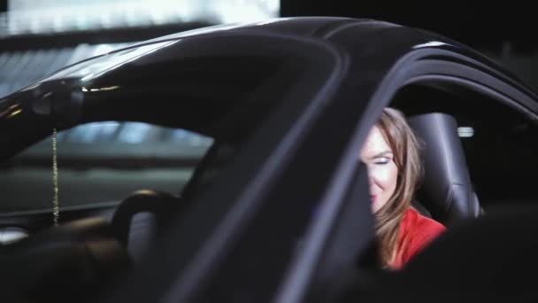Lüks araba binmeye hazır kırmızı elbiseli seksi kadını sürücüsü — Stok video