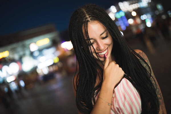 Sexy attractive woman holding finger on lips in night city street