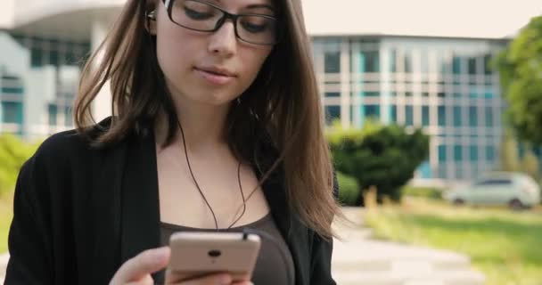 Mujer escuchando música o audiolibro mientras camina por el centro de la ciudad — Vídeo de stock