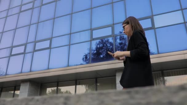 Mujer de negocios usando smartphone contra edificio de oficinas alto, vista inferior — Vídeos de Stock