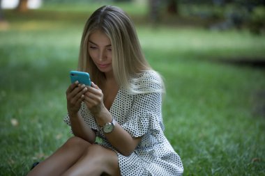 Çimenlerin üzerinde telefon kullanan kadın