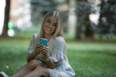 Çimenlerin üzerinde telefon kullanan kadın