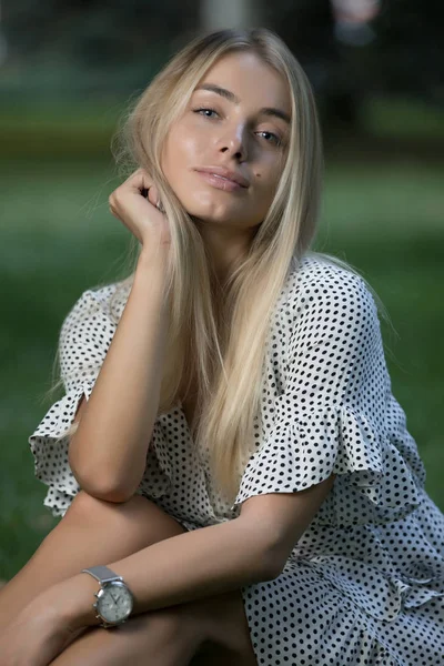 Çimenlerin üzerinde oturan mavi gözlü güzel kadın