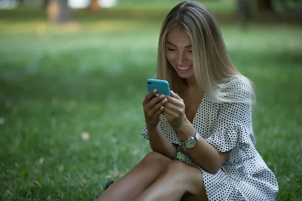 Çimenlerin üzerinde telefon kullanan kadın