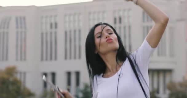 Joyeuse femme dansant en écoutant de la musique en ville avec un téléphone portable — Video