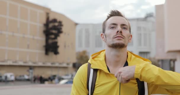 Retrato de un joven caucásico vestido con una elegante chaqueta amarilla en la plaza de la ciudad urbana — Vídeo de stock