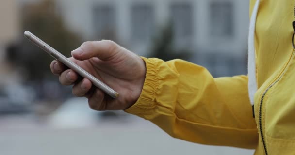 Männliche Hand in gelber Jacke schaltet Smartphone-App hoch und gefällt einigen Posts — Stockvideo