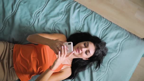 Donna scrivere messaggio dal telefono cellulare sdraiato sul letto, vista dall'alto — Video Stock