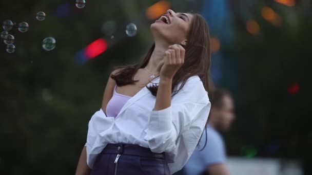 Щаслива доросла дівчина ловить бульбашки в парку — стокове відео