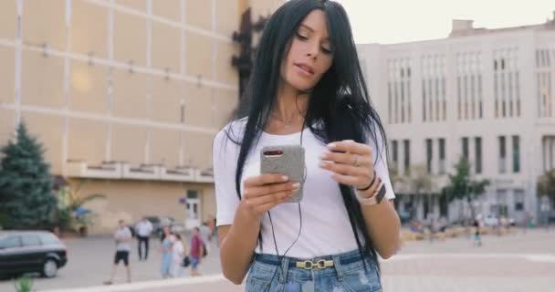 Женщина слушает музыку с мобильного телефона в городе — стоковое видео