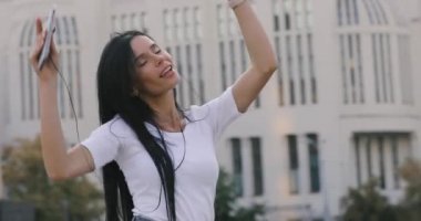 Neşeli kadın şehir cep telefonu ile müzik dans