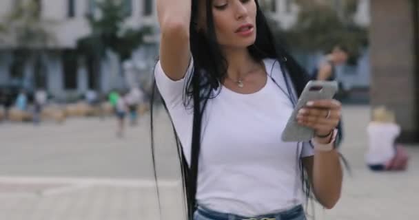 Сумасшедшая женщина танцует, слушая музыку в городе с мобильного телефона — стоковое видео