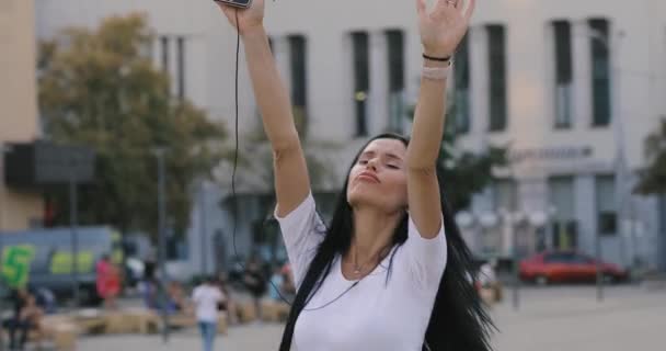 Женщина танцует, слушая музыку с мобильного телефона — стоковое видео