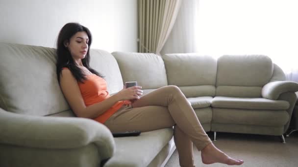 Женщина переключает телевизионные каналы расслабляясь дома — стоковое видео