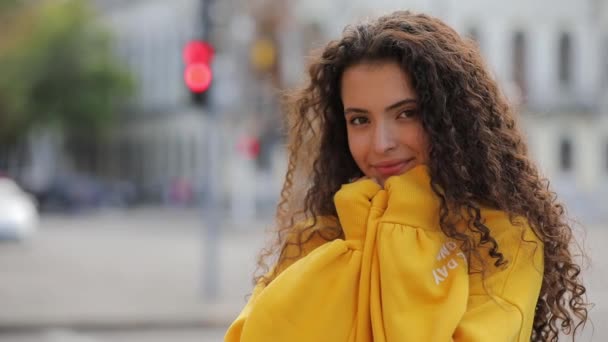 Mignon jeune fille bouclée en jersey jaune, fond urbain de la ville — Video