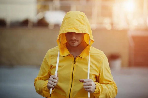 Runner man athlete under yellow hood of sportswear