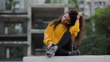Kentsel şehirde oturan moda sarı kazaklı genç kız