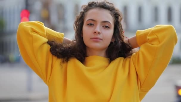 Lachende leuk krullend tiener meisje portret in gele trui, stedelijke stad achtergrond — Stockvideo